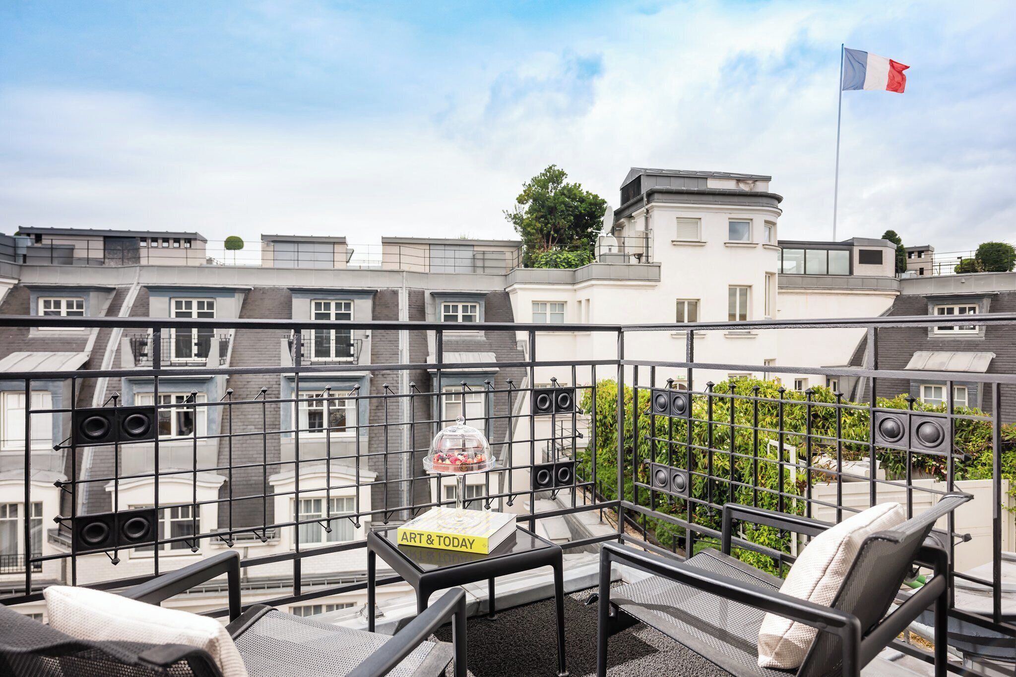 A balcony with a table, chairs, and a book titled 'ART & TODAY'.