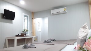 A hotel room with a bed, bedside table, TV, air conditioning unit, and a window. - Barbados Terrace (Rayong)