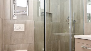 A modern bathroom with a glass-enclosed shower, a white toilet, and a sink with a mirror above it. - Fitzroy Serviced Apartments by Concept Apartments (London)