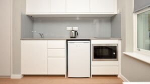 A modern kitchen with white cabinetry, a built-in dishwasher, a microwave, and a kettle. - Fitzroy Serviced Apartments by Concept Apartments (London)