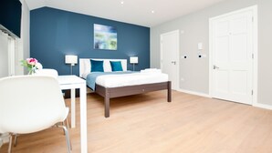 A modern bedroom with a bed, bedside tables, a chair, and a painting on the wall. - Fitzroy Serviced Apartments by Concept Apartments (London)
