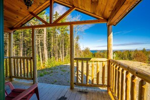 A wooden deck with a view of a forest and distant mountains. - Bluff House Inn (Gouldsboro)