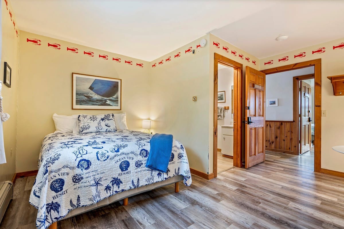 Un dormitorio con cama, un cuadro y una puerta de madera que da a otra habitación.
