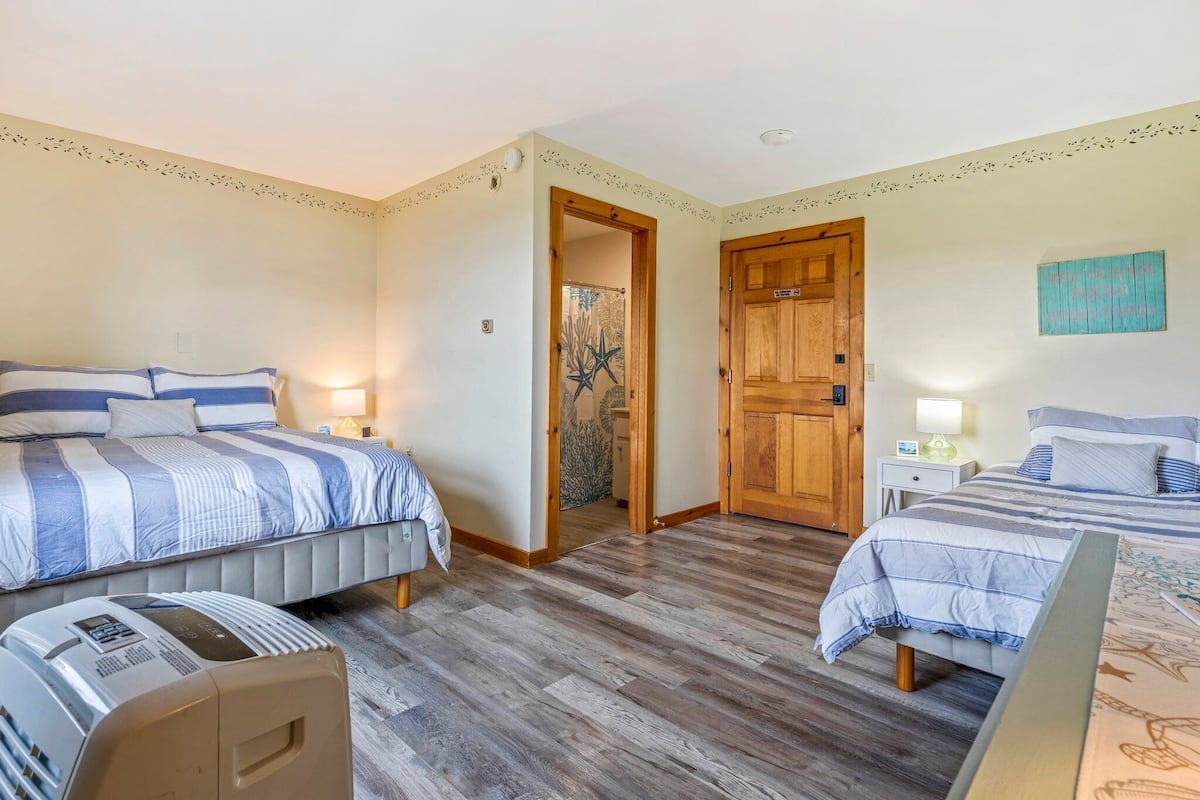 Un dormitorio con dos camas, suelo de madera y una puerta de madera.