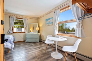A cozy room with a bed, a dresser, a table with chairs, and a window with curtains. - Bluff House Inn (Gouldsboro)