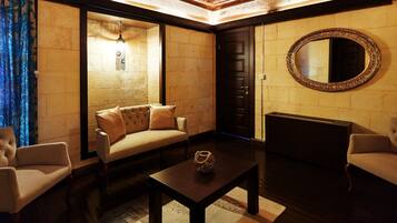 A cozy room with a sofa, armchairs, a coffee table, and a mirror on the wall.