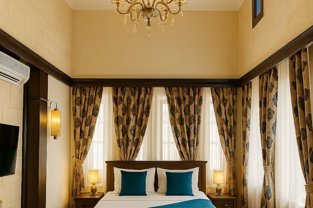 Quarto de hotel com uma cama grande, um lustre e cortinas.