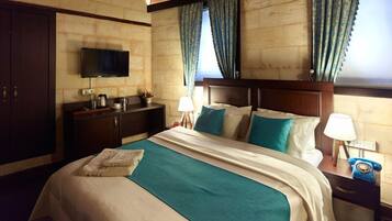 A hotel room with a bed, a TV, a desk with a lamp, and a telephone.