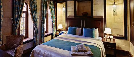 A traditional room with a large bed, wooden beams, and a stone wall.