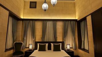 A hotel room with a large bed, two nightstands, a chair, and a ceiling with decorative moldings.