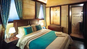 A hotel room with a large bed, wooden headboard, two bedside lamps, a nightstand, and a view of the bathroom.