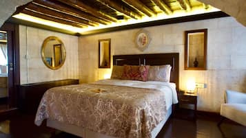 Un dormitorio con una cama grande, techo de madera, un espejo redondo y una mesita de noche con lámpara.