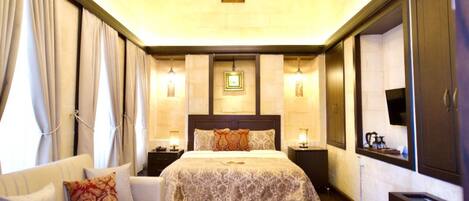 Habitación de hotel con una cama grande, un sofá, una mesa de centro y un candelabro.