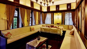 Una habitación con sofá, una mesa con mantel de encaje y un candelabro.