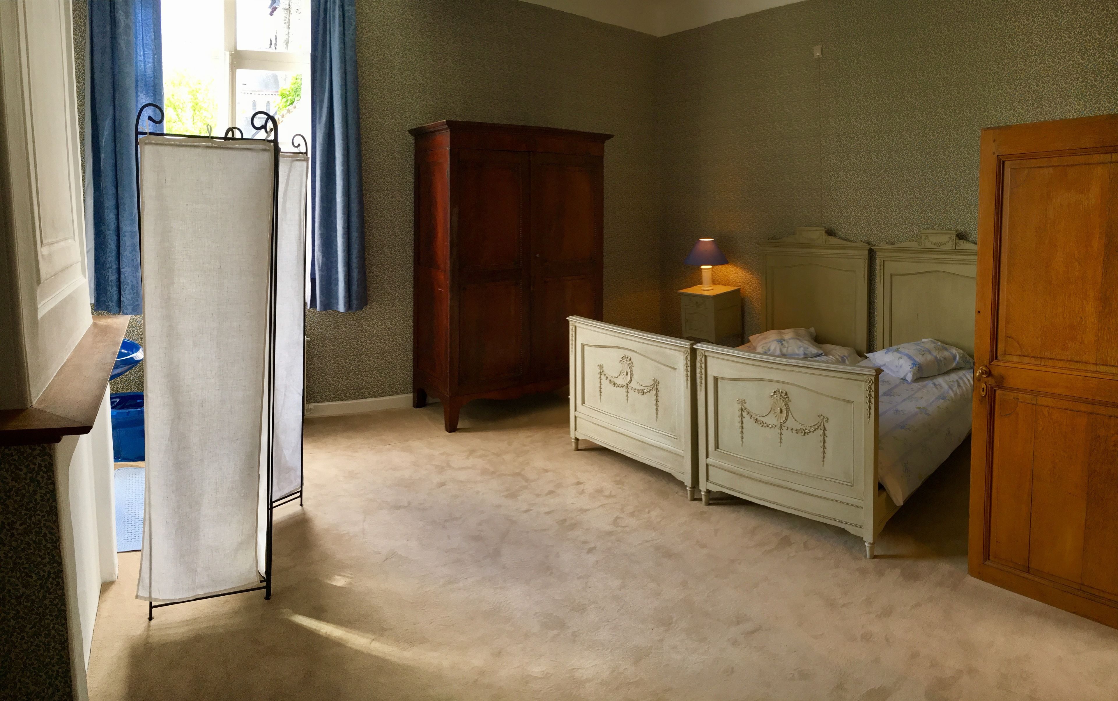 Et soveværelse med seng, to sengeborde, en kommode, et klædeskab og et vindue med gardiner.