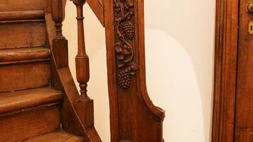 A wooden staircase with intricate carvings and a door with a brass handle.