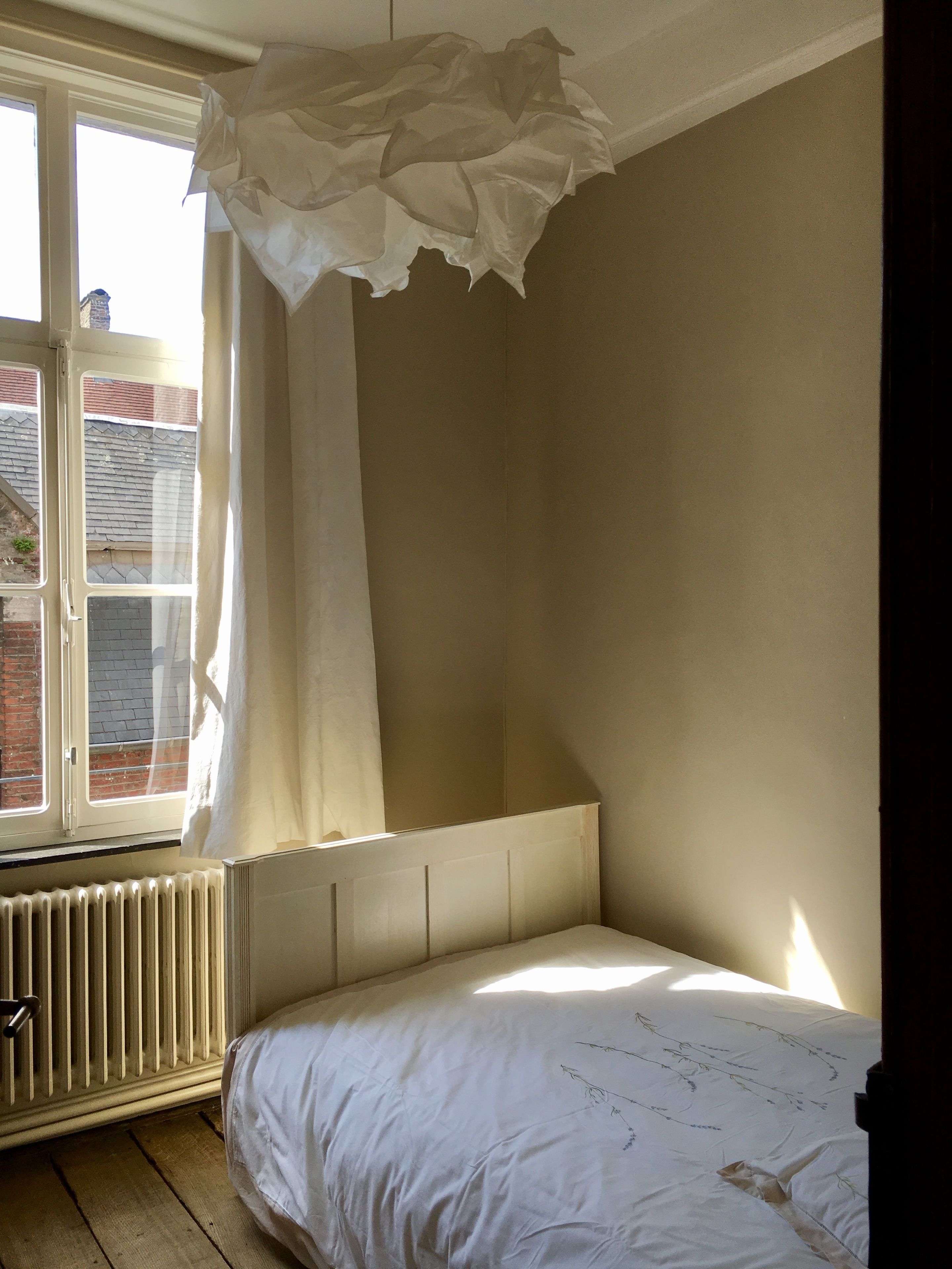 A bedroom with a bed, a window, and a radiator.