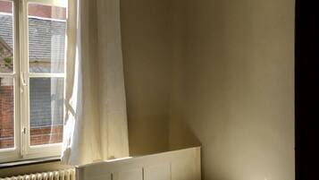A bedroom with a bed, a window, and a radiator.