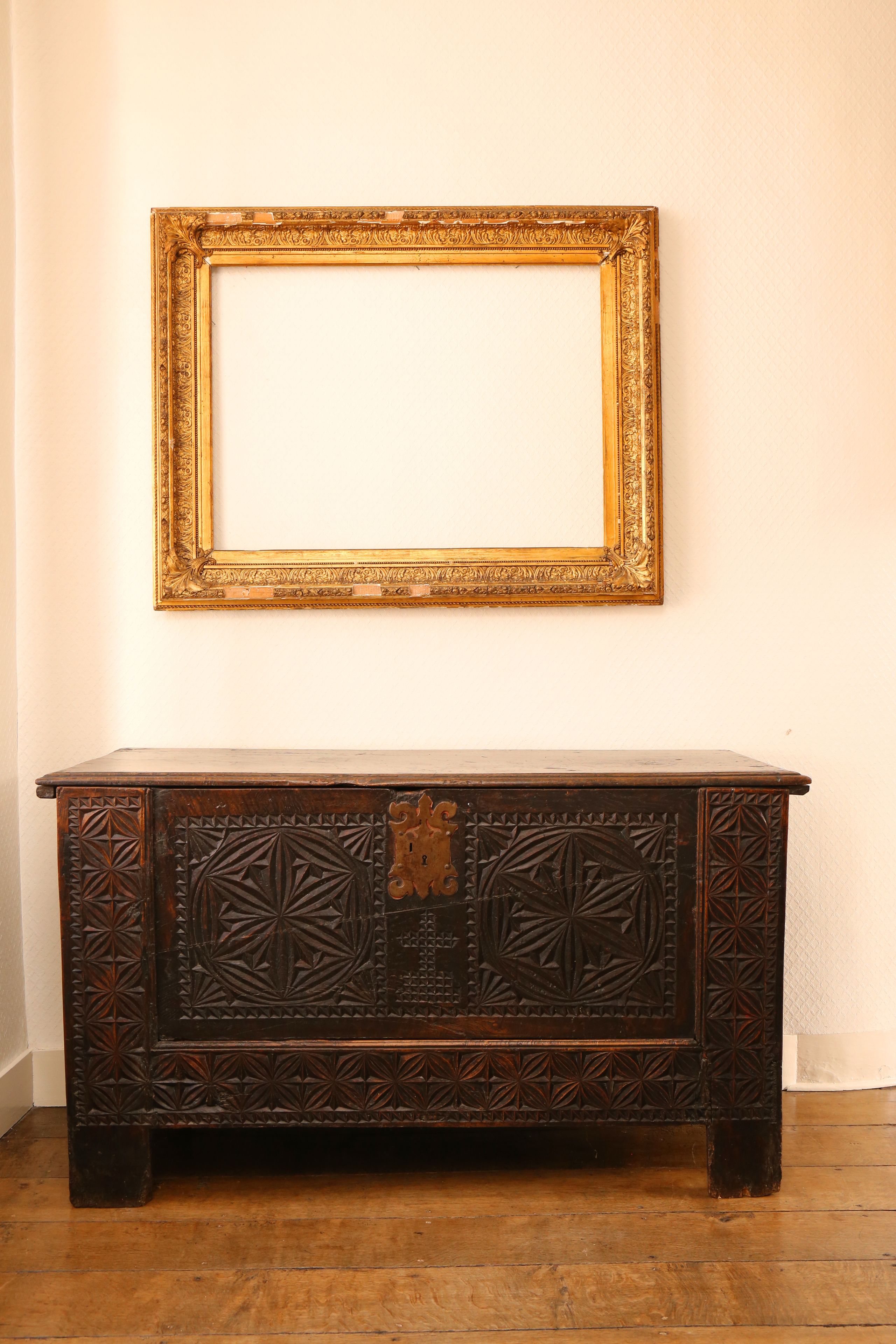 A dark wooden cabinet with intricate carvings and a gold-framed mirror above it.