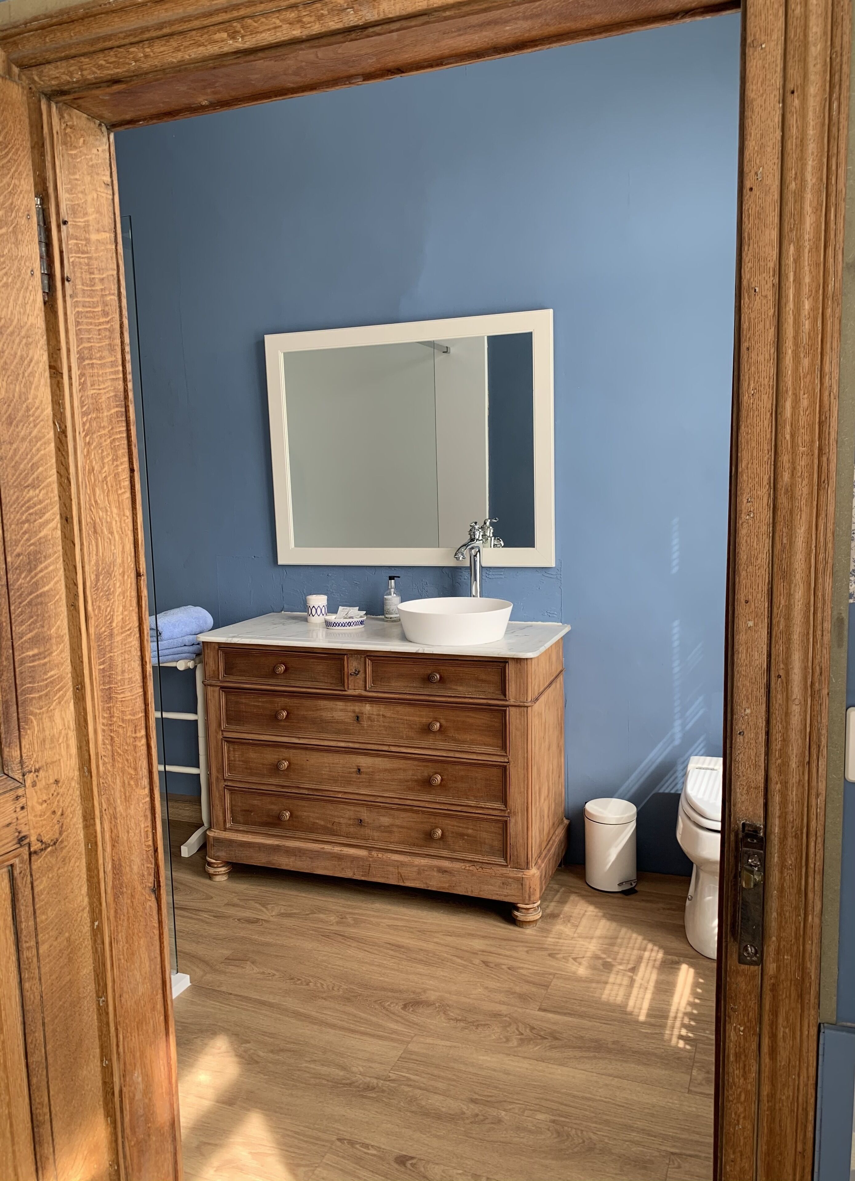 A bathroom with a wooden vanity, a white sink, and a large mirror.