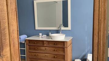 A bathroom with a wooden vanity, a white sink, and a large mirror.