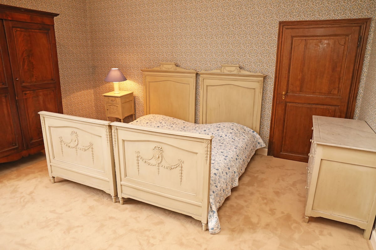 Ein Schlafzimmer mit einem Bett, zwei Kommoden, einem Nachttisch und einer Lampe.