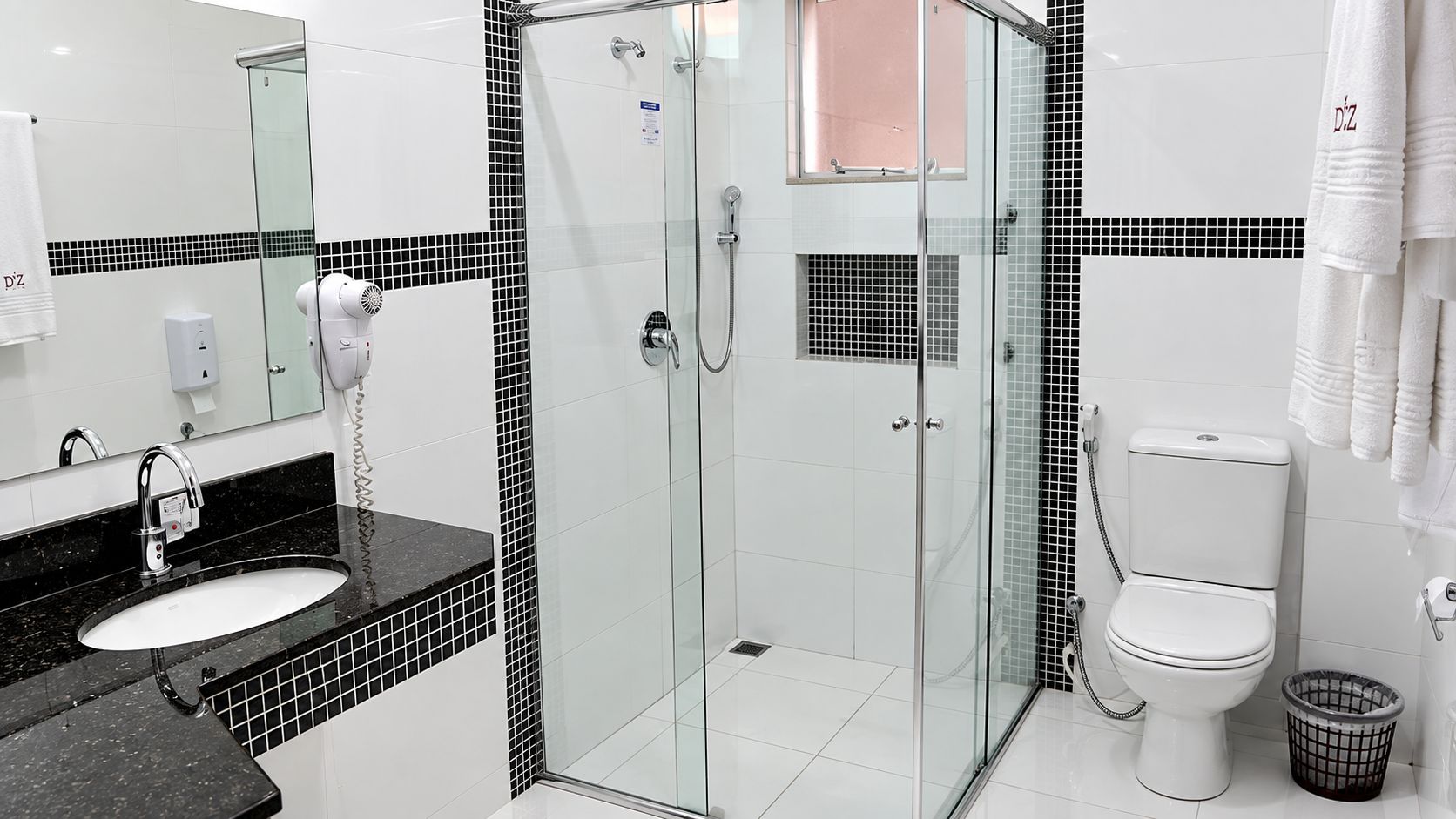 A modern bathroom with a glass-enclosed shower, a white toilet, and a black countertop sink.
