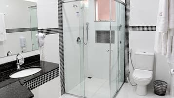 A modern bathroom with a glass-enclosed shower, a white toilet, and a black countertop sink.