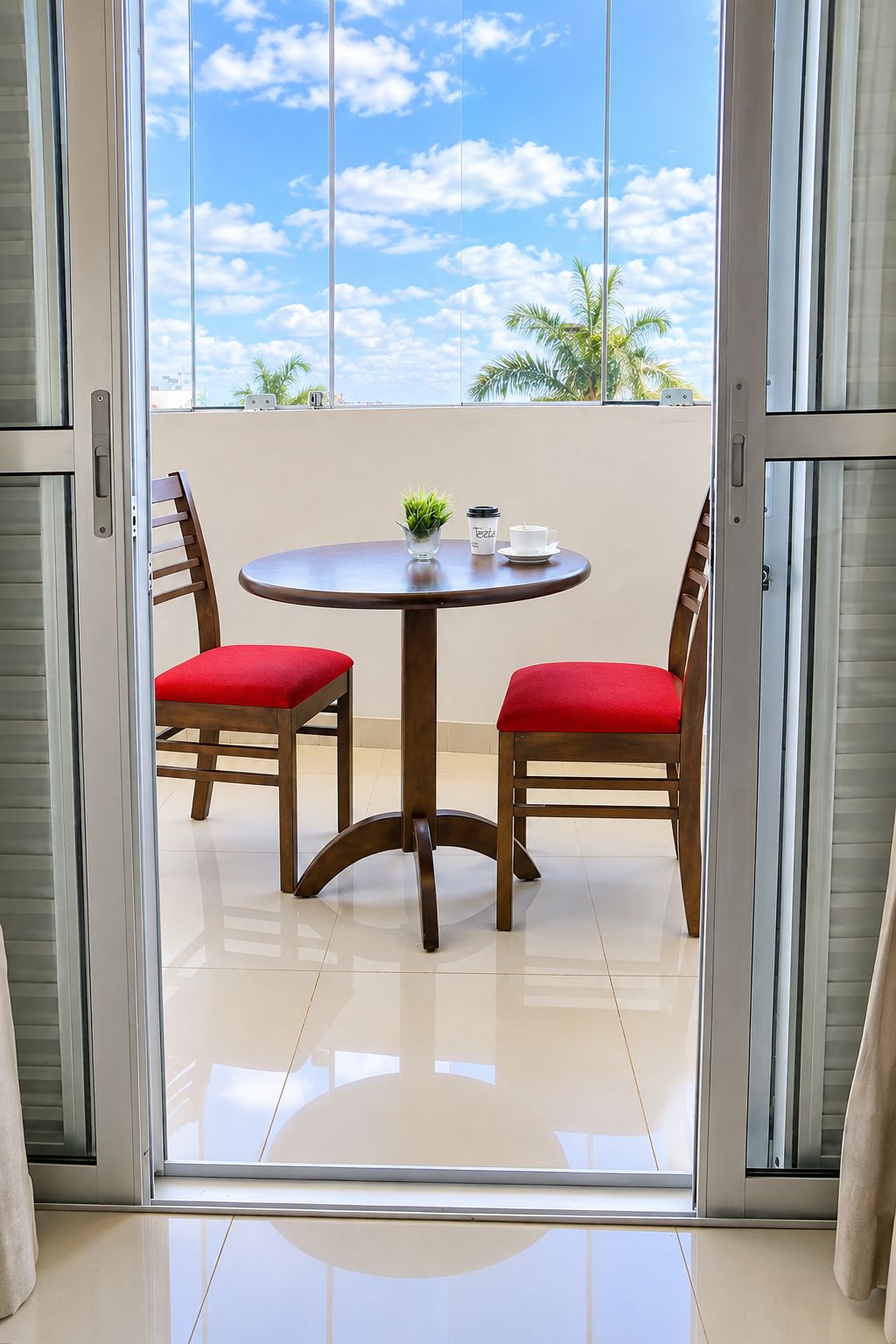 A balcony with a table and chairs, a potted plant, and a coffee cup.