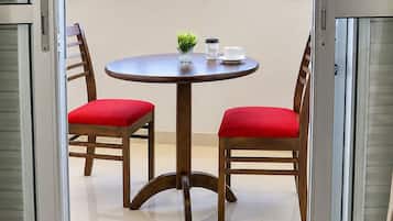 A balcony with a table and chairs, a potted plant, and a coffee cup.