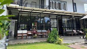 A two-story building with a covered outdoor seating area, large windows, and a balcony. - Sherloft Home & Hostel (Chiang Mai)
