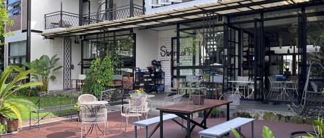 A modern building with a patio area featuring outdoor seating and potted plants.