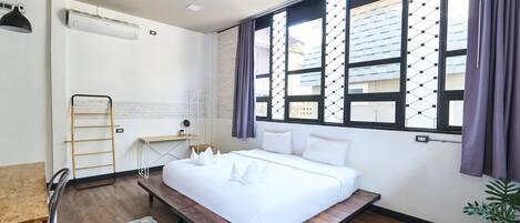 Un dormitorio moderno con una cama grande, un banco de madera, un escritorio y una silla.