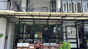 A hotel entrance with a covered outdoor seating area, a staircase, and a view of the street. - Sherloft Home & Hostel (Chiang Mai)
