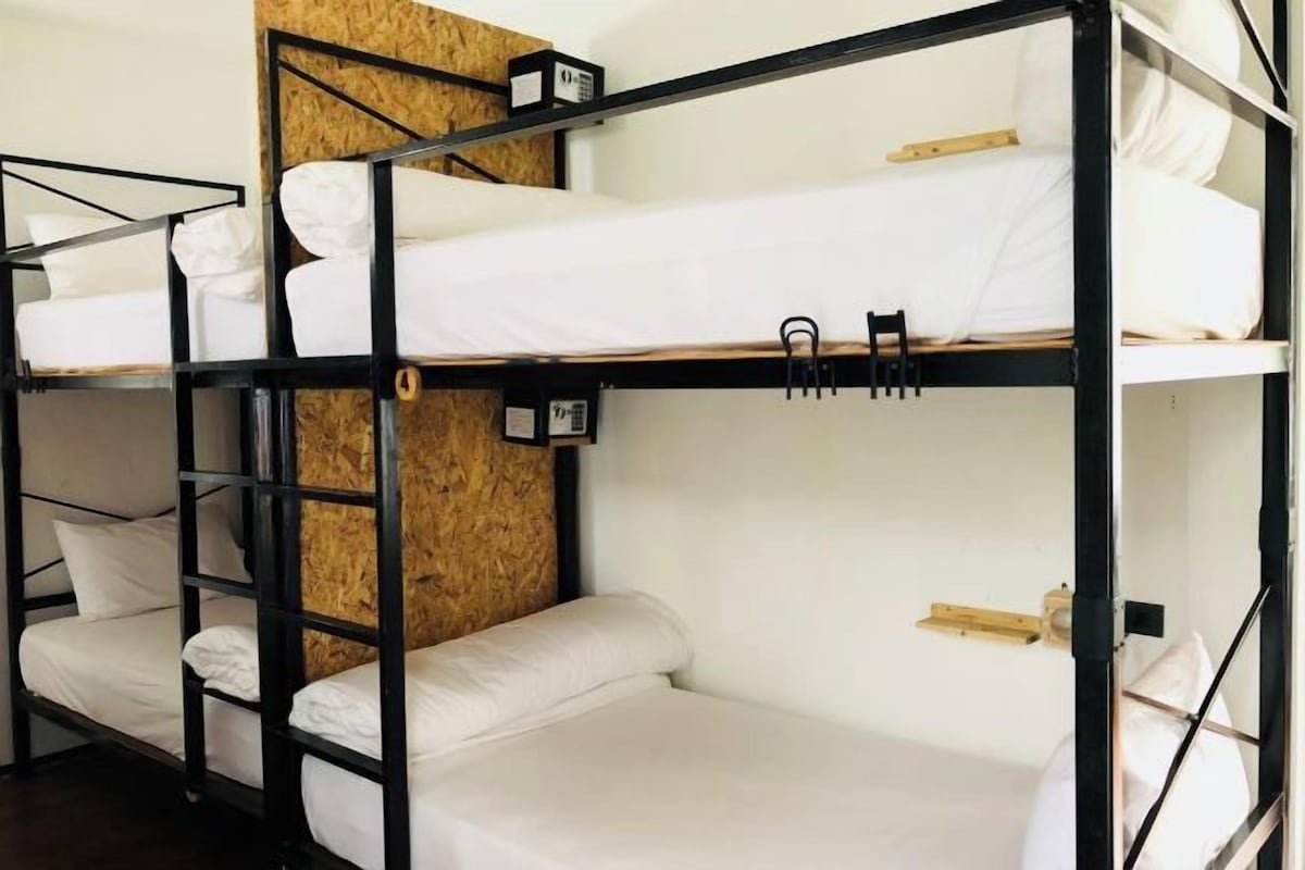 A bunk bed room with white bedding and a wooden headboard.