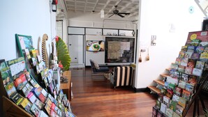 A room with wooden flooring, a ceiling fan, a television, and a window with a map. - Sherloft Home & Hostel (Chiang Mai)