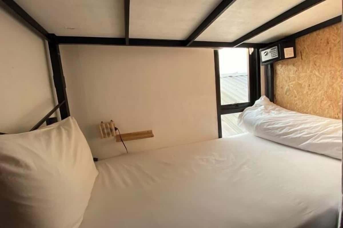 A single bed with white bedding, a wooden headboard, and a window with a view.