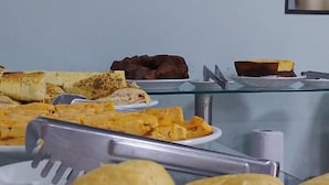 Buffet com diversos alimentos, incluindo tortillas, quesadillas e um prato de doces dourados.