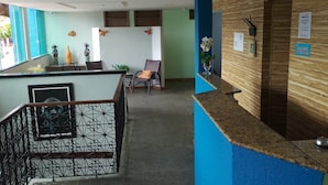 Uma área de recepção com balcão azul, mesa de madeira e uma cadeira.