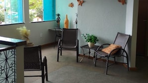 Um quarto com duas cadeiras de vime, uma mesinha e um vaso de planta.