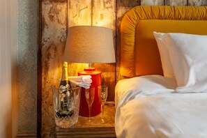 A hotel room with a wooden headboard, a red nightstand, a lamp, two champagne flutes, and a white pillow. - House Dublin (Dublin)