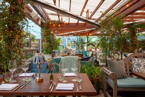 An outdoor dining area with wooden tables, chairs, and string lights. - House Dublin (Dublin)