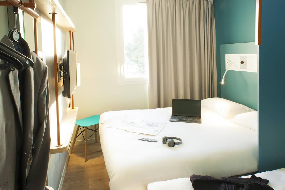 Een hotelkamer met twee bedden, een bureau, een laptop en een stoel.