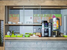 Una kitchenette equipada con cafetera, dispensador de agua y refrigerador.