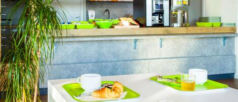 Una cocina moderna con zona de desayuno que incluye croissants, jugo y café.