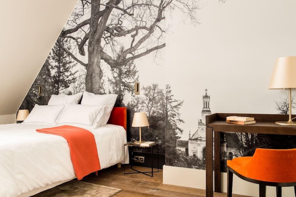 A bedroom with a bed, nightstands, a desk, and a chair.