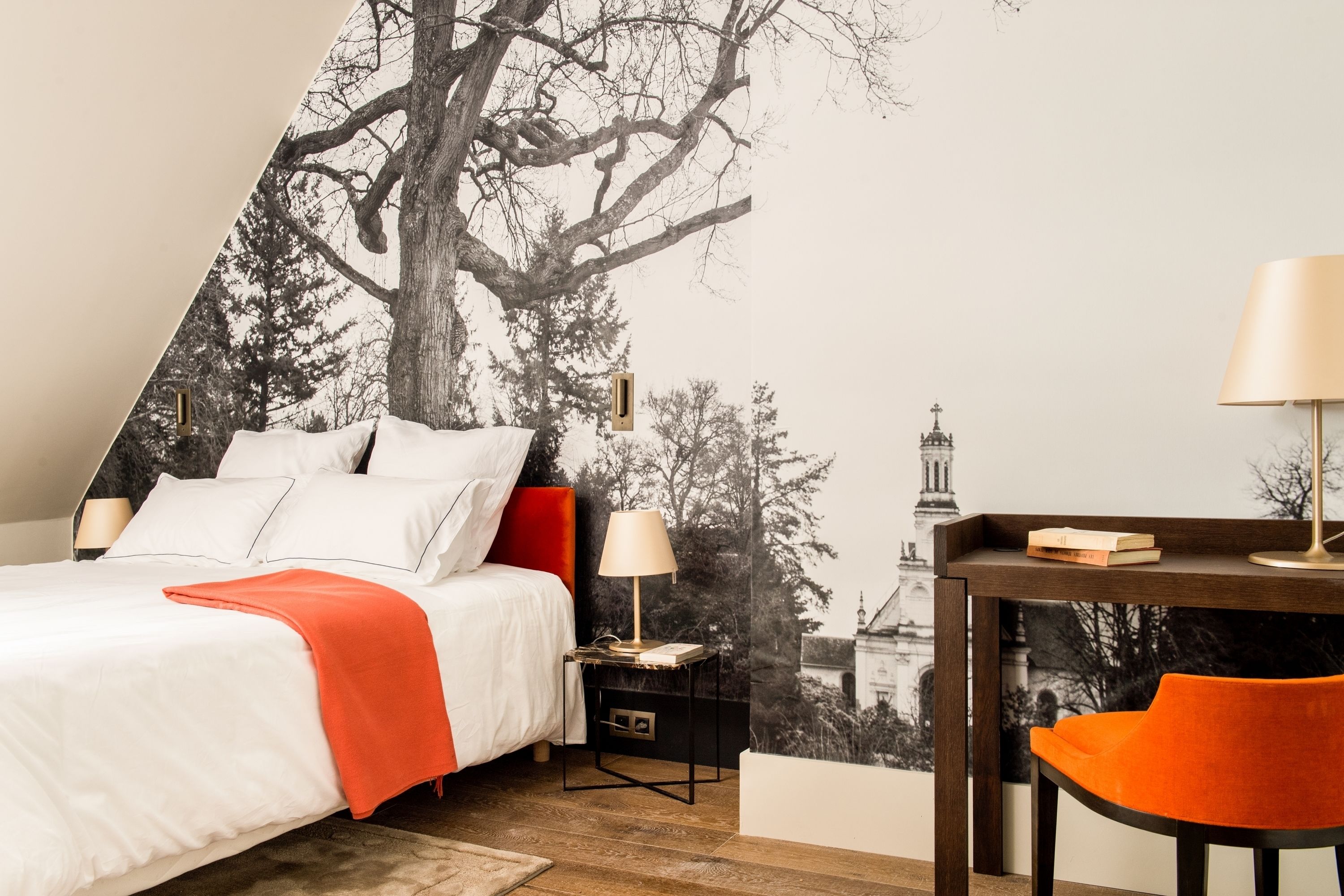 Een slaapkamer met een bed, nachtkastjes, een bureau en een stoel.