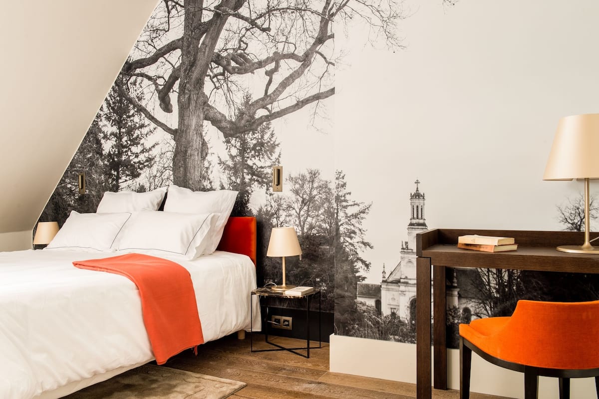 A bedroom with a bed, bedside tables, a desk, and a chair.