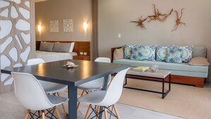 A modern hotel room with a dining area, a sofa with patterned cushions, and decorative wall art. - Splendid 1 bedroom by Happy Address (Playa del Carmen)