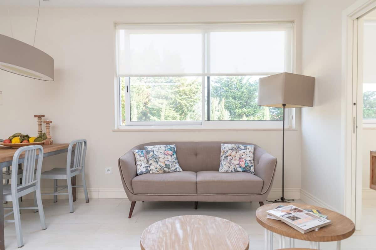 A modern living room with a sofa, a round coffee table, and a dining table with chairs.